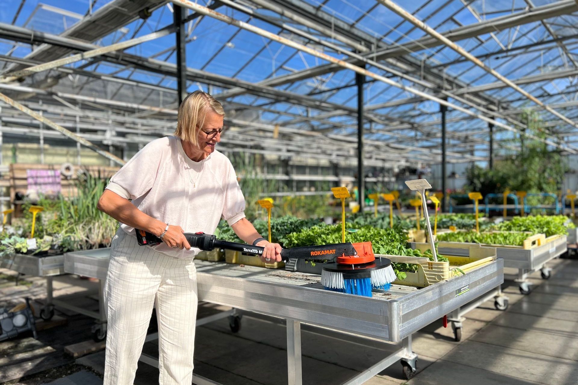 Picture of a woman working with our Greeny PRO®, the machine for cleaning nursery tables.