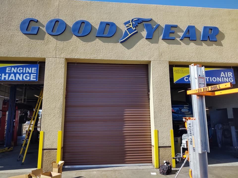 Exterior of a commercial building with roll-up doors and a modern design. The building has a light beige facade and dark gray trim.