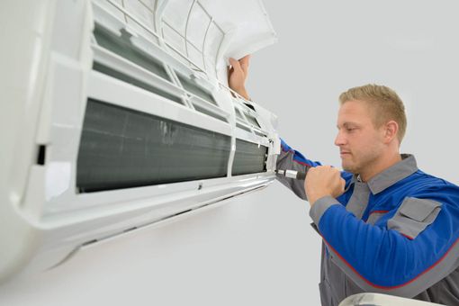 Heating Ogden — A Man Repairing an Air Conditioner in Ogden, UT