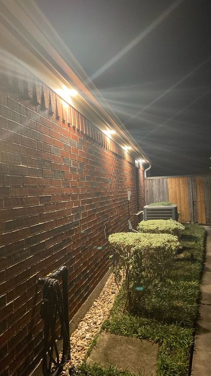 A brick wall with lights on it is lit up at night.