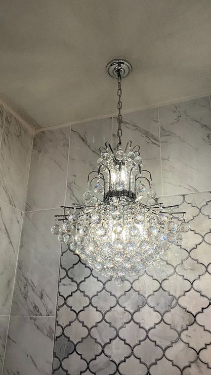 A chandelier is hanging from the ceiling in a bathroom.