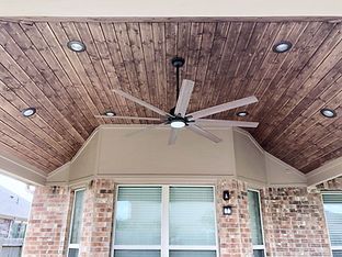 A ceiling fan is hanging from the ceiling of a porch.