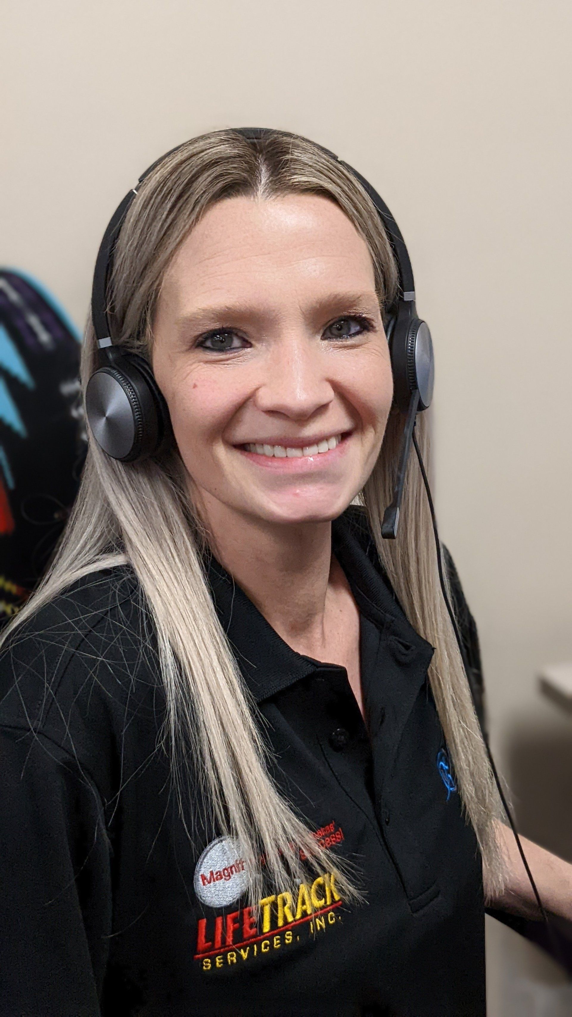 Woman with headset smiling, wearing a black shirt with
