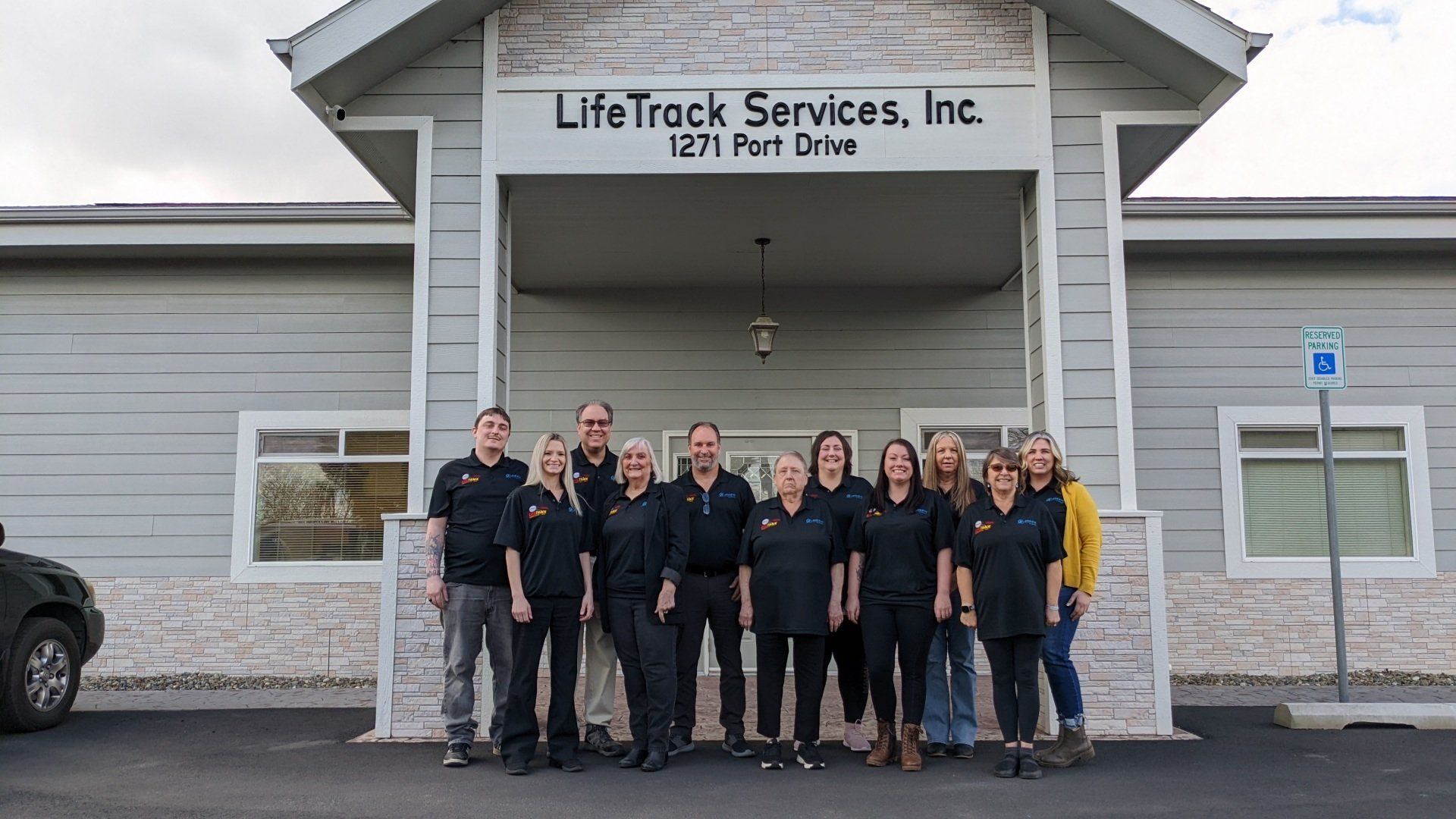 Group of people standing outside LifeTrack Services, Inc. building. All are wearing black shirts.