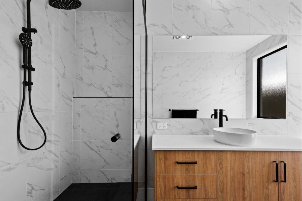 A bathroom with a sink , shower and mirror.— Peter Betros Homes in Highfields, QLD
