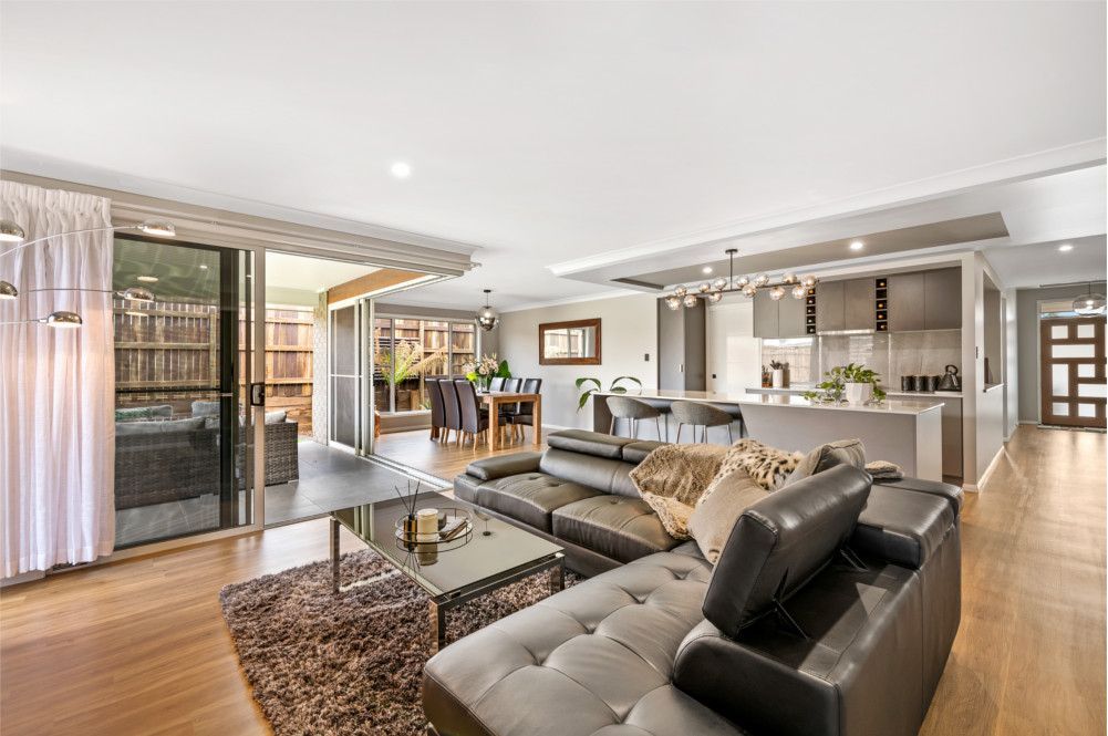 A living room with a couch , coffee table , and rug. — Peter Betros Homes in Highfields, QLD