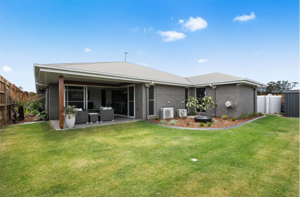 A bedroom with a large bed , a ceiling fan , and a window. — Peter Betros Homes in Highfields, QLD