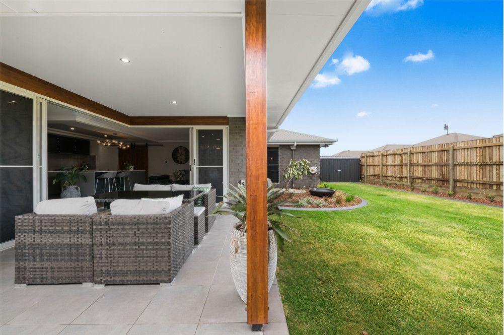 A patio with furniture and a fence in the backyard of a house. — Peter Betros Homes in Highfields, QLD