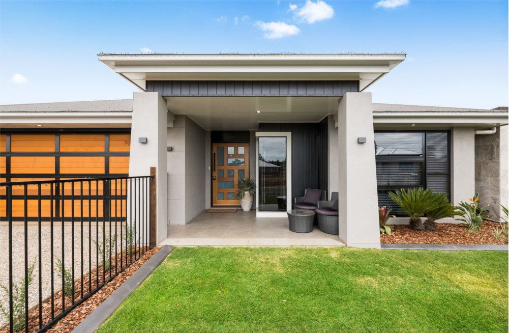 The front of a modern house with a fence and a large porch. — Peter Betros Homes in Highfields, QLD