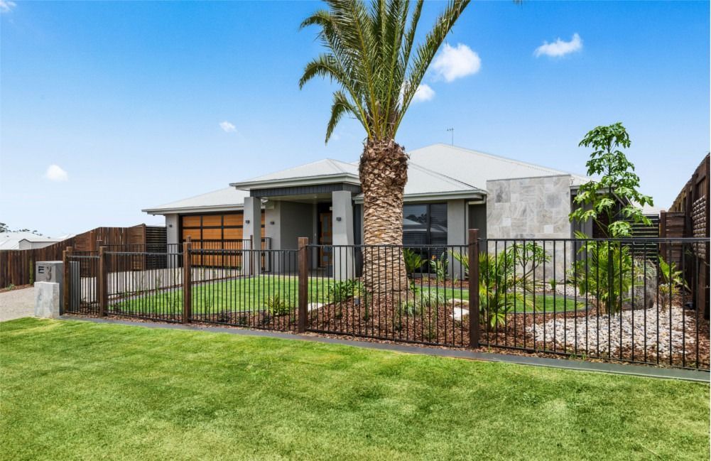 A House With a Tree in Front of It and a Fence Around It — Peter Betros Homes in Highfields, QLD