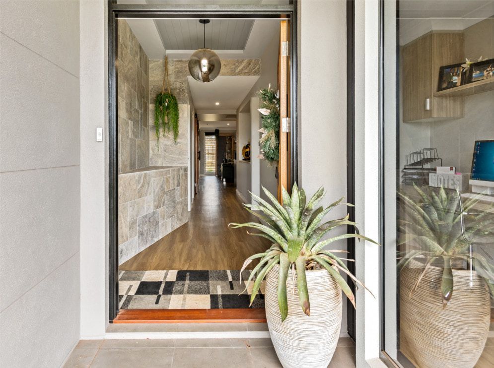 A potted plant is sitting in the doorway of a house. — Peter Betros Homes in Highfields, QLD