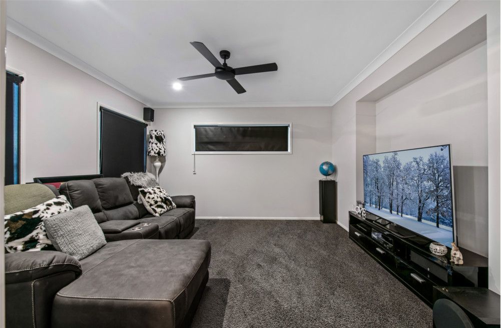 A living room with a couch , television , and ceiling fan. — Peter Betros Homes in Highfields, QLD