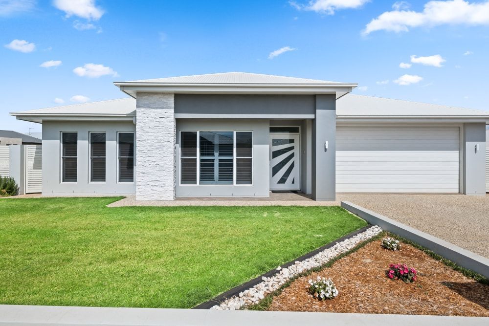 A large white house with a lush green lawn in front of it. — Peter Betros Homes in Highfields, QLD