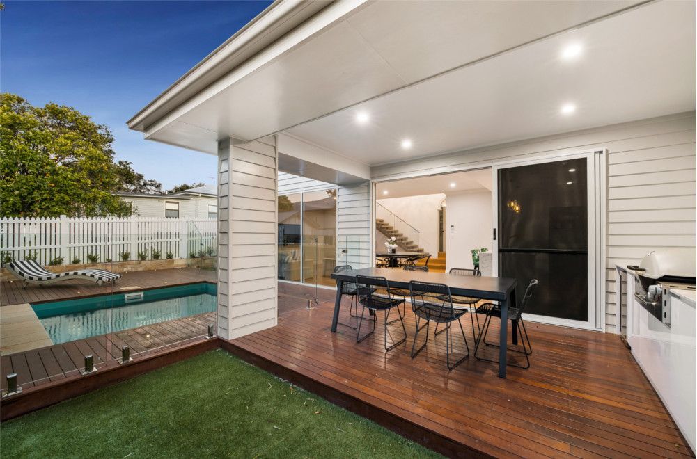 A patio with a table and chairs next to a swimming pool. — Peter Betros Homes in Highfields, QLD