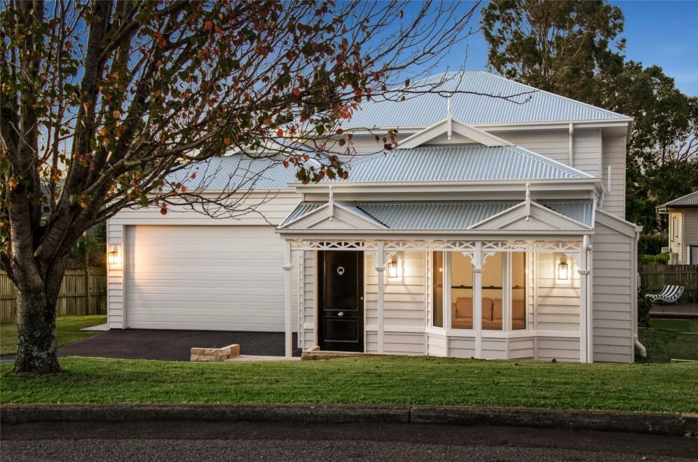 A White House With a Blue Roof is Sitting on Top of a Lush Green Lawn — Peter Betros Homes in Highfields, QLD