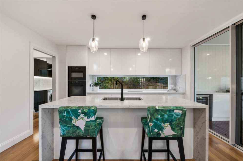 A kitchen with a large island and two bar stools. — Peter Betros Homes in Highfields, QLD