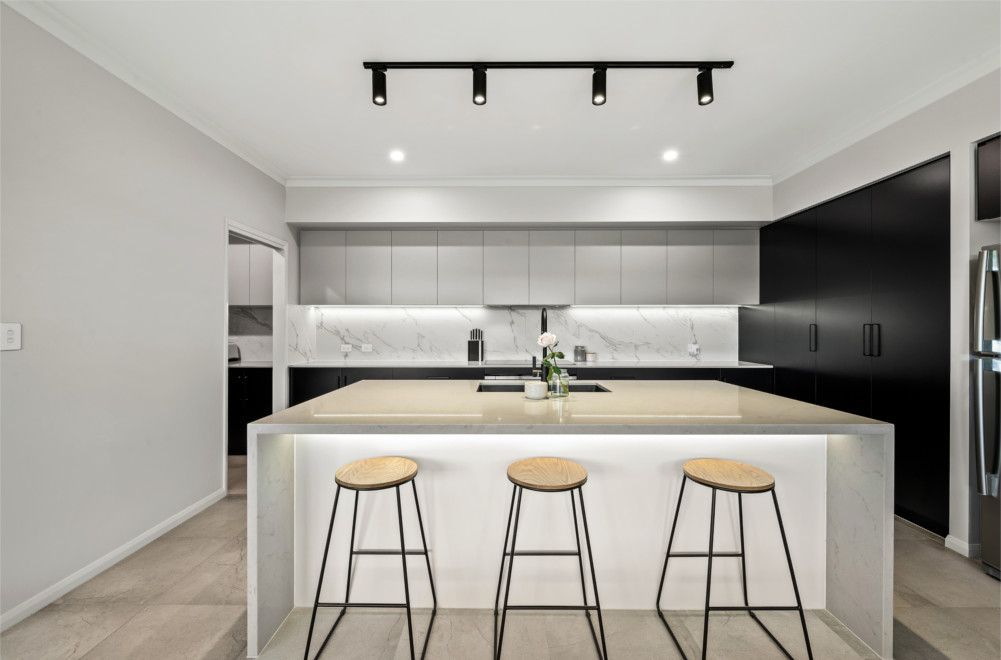 A Kitchen with A Large Island and Three Stools — Peter Betros Homes in Highfields, QLD