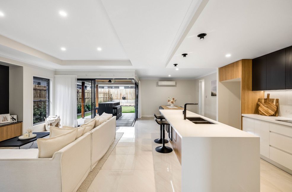 A Living Room and Kitchen in A House with A Large Island in The Middle — Peter Betros Homes in Highfields, QLD