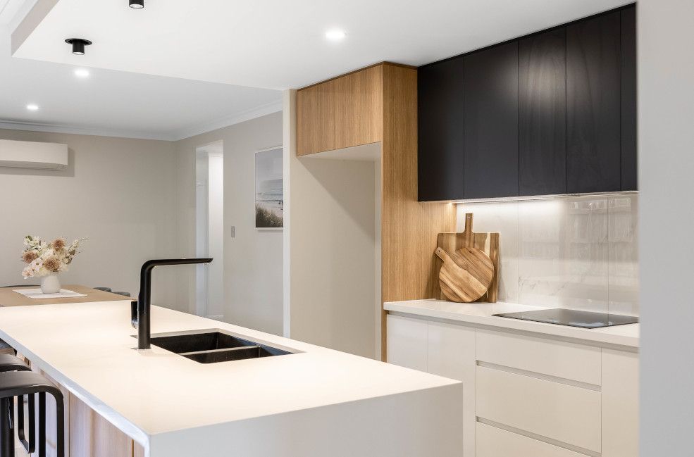 A Kitchen with Black Cabinets, White Counter Tops, and A Sink — Peter Betros Homes in Highfields, QLD