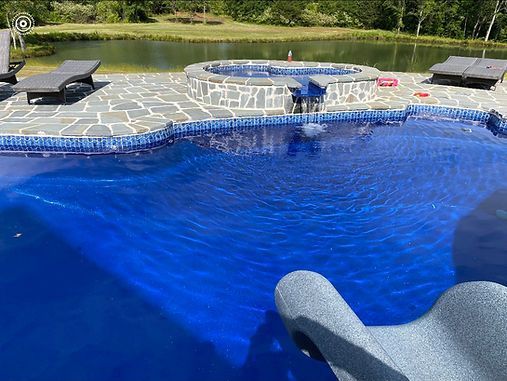 A large swimming pool with a hot tub in the middle of it.