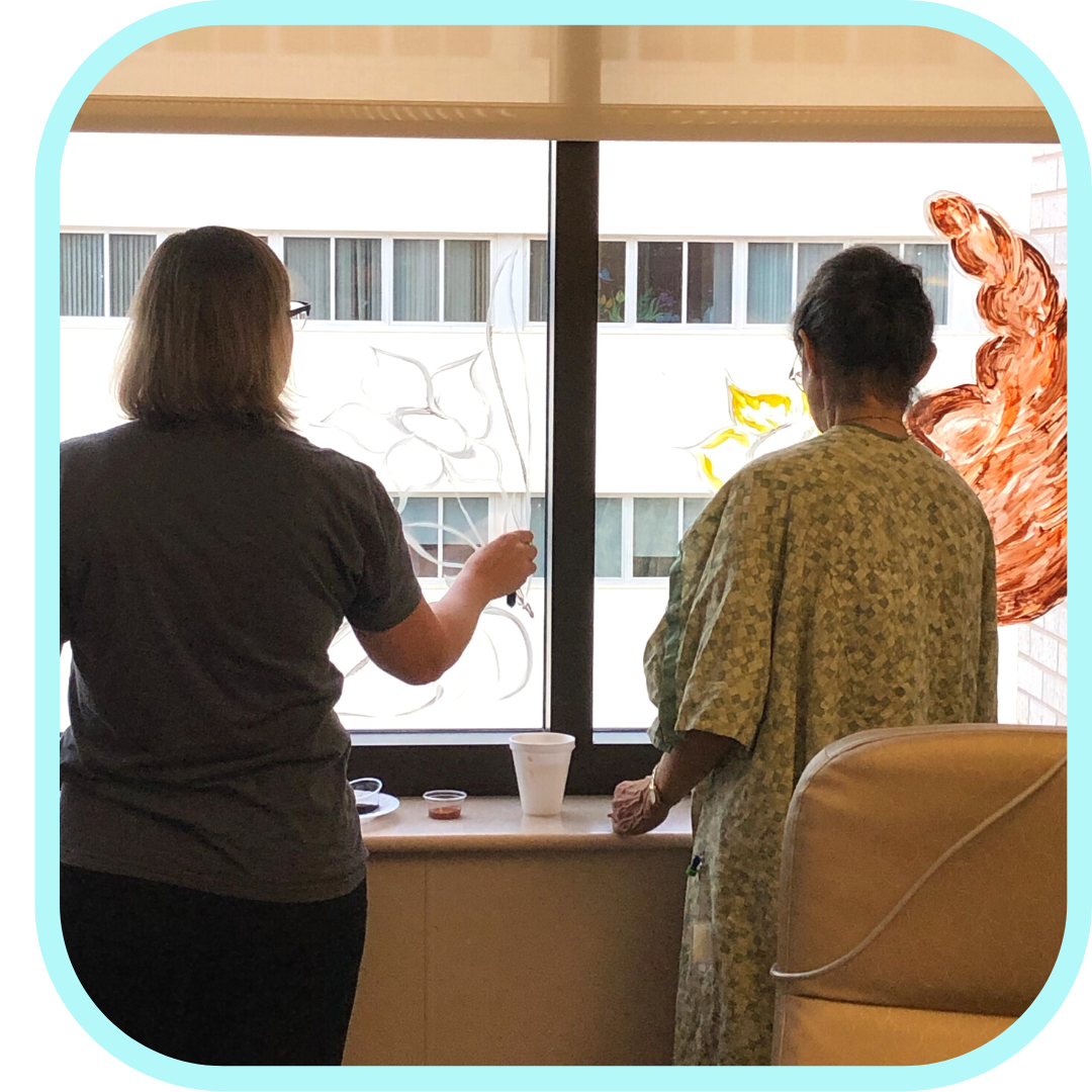 two people painting on a hospital room window