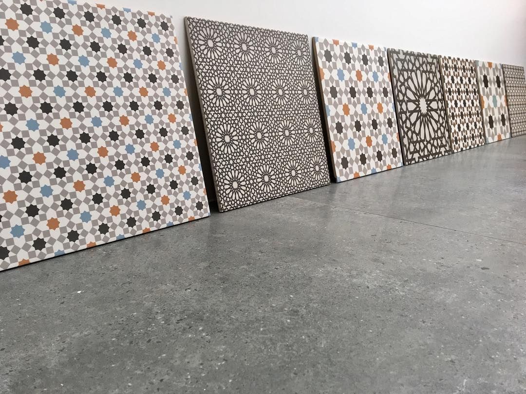 A Row of Tiles With Different Designs Are Lined Up on a Concrete Floor