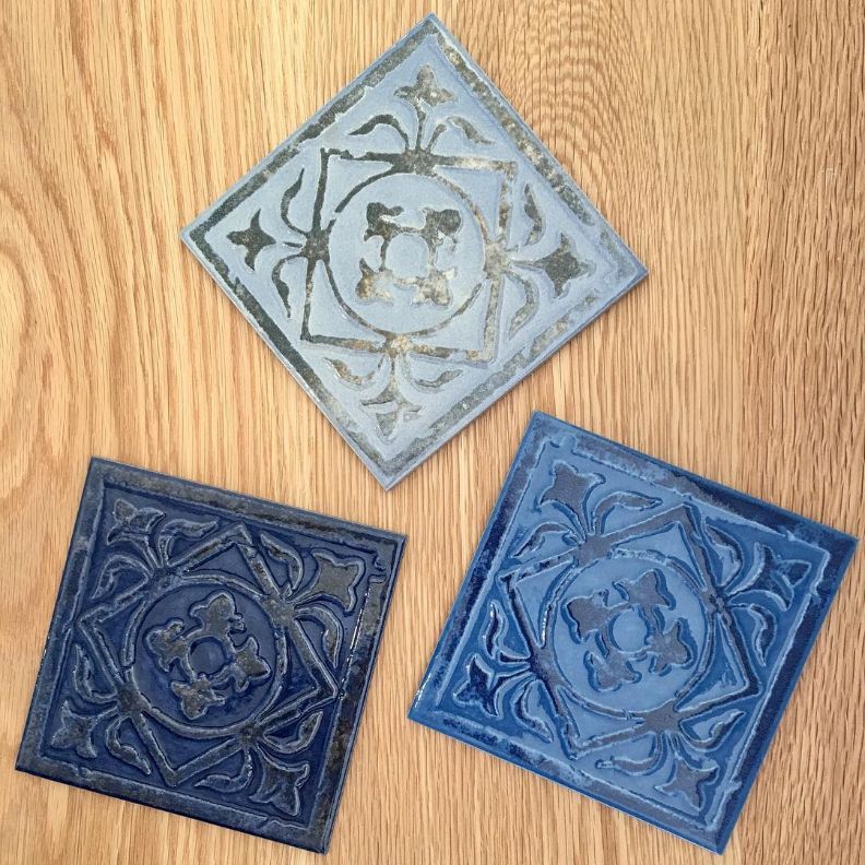 Three Blue Tiles Are Sitting on a Wooden Table — Dean Gray Tiling in Banora Point, NSW