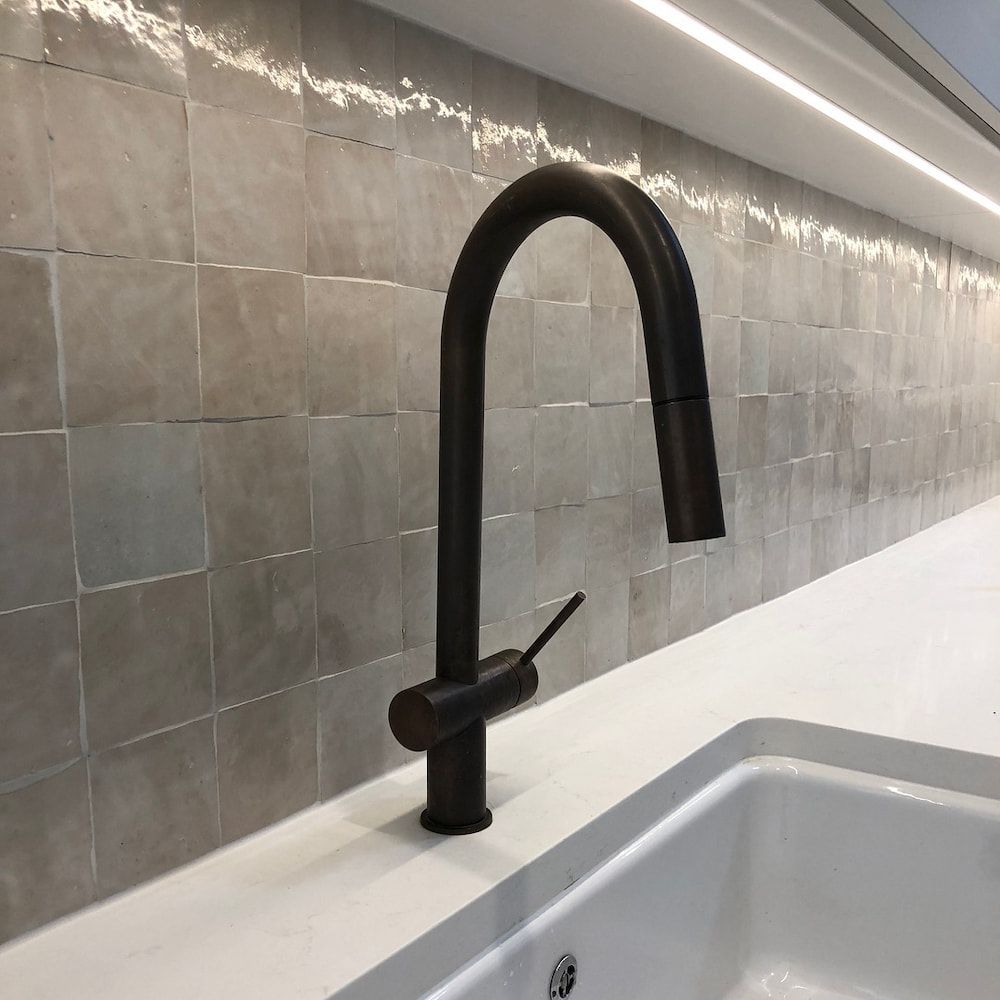 A Black Faucet is Sitting on a Counter Next to a Sink — Dean Gray Tiling in Murwillumbah, NSW