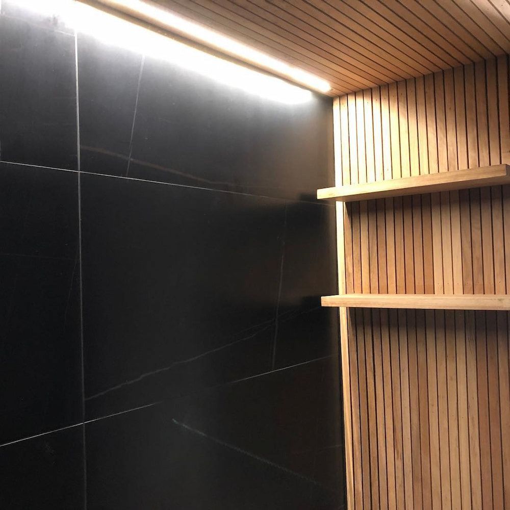 A Room With Black Tiles and Wooden Shelves — Dean Gray Tiling in Palm Beach, QLD