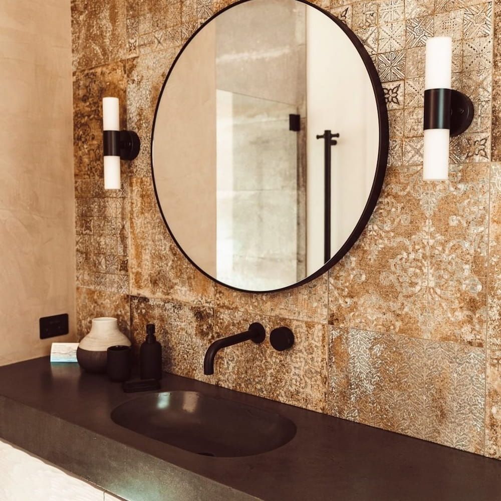 A Bathroom With a Round Mirror and a Sink — Dean Gray Tiling in Robina, QLD