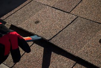 A person wearing red and black gloves is working on a roof.