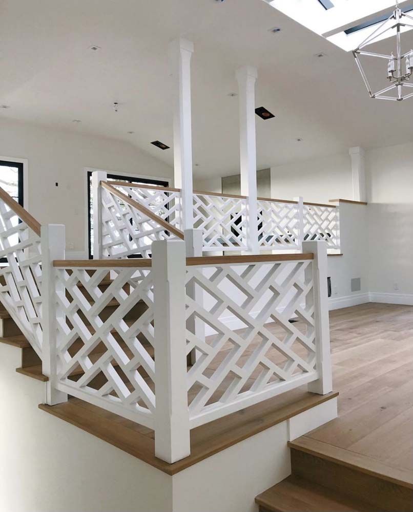 White geometric railing on a wooden staircase and landing in a bright, modern interior.