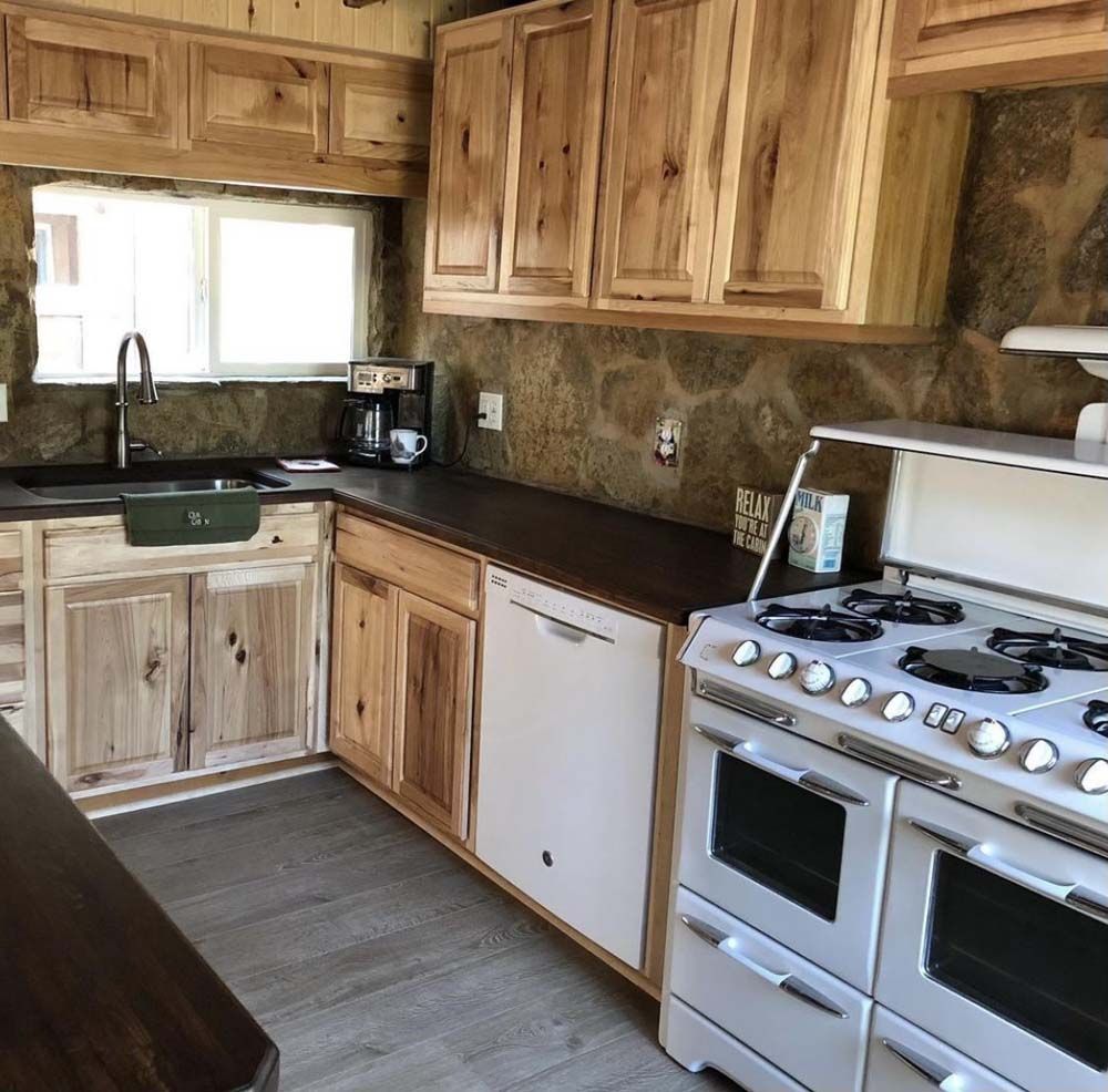 Rustic kitchen with light wood cabinets, dark countertops, and a white oven.