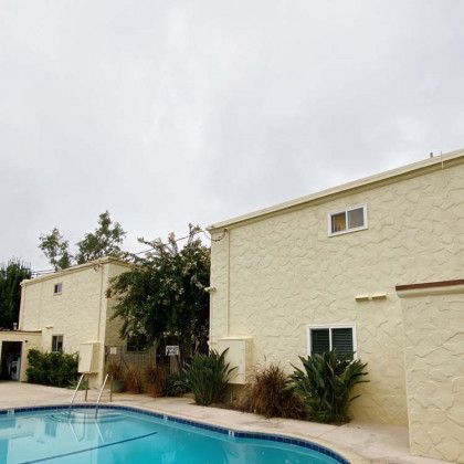 Apartment buildings next to a swimming pool, cloudy sky overhead.