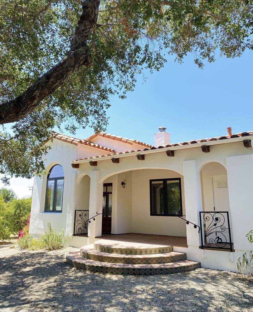 White stucco home with a terracotta tile roof, arched windows, and a covered porch.