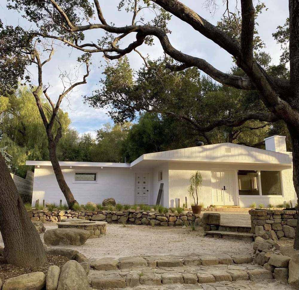 White modern house with landscaping and trees.