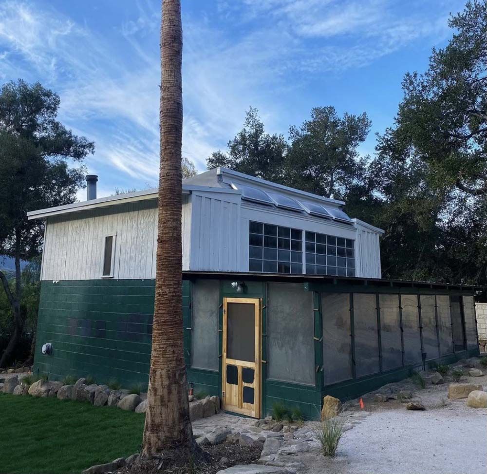 Two-story white and green building with solar panels on the roof. 