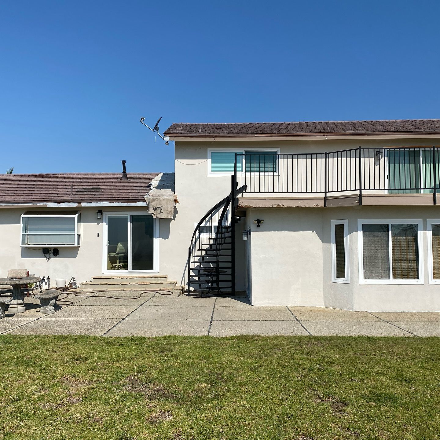 Two-story house with a spiral staircase, and a concrete patio.