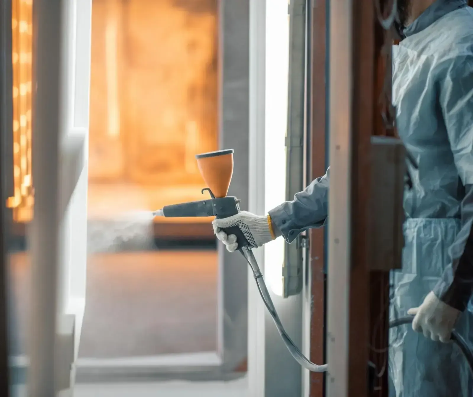 A person in a white shirt and jeans connects tubing to a Carrier air conditioning unit outdoors.