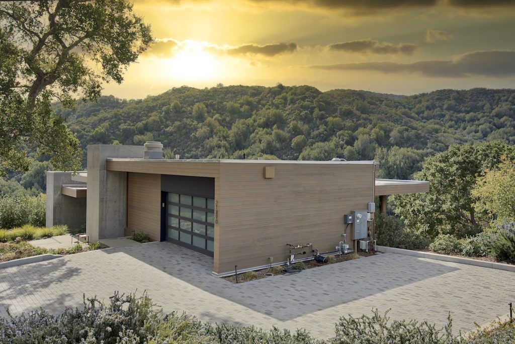 Construction worker in a safety vest and hard hat holds a wrench, looking at it with a questioning expression.