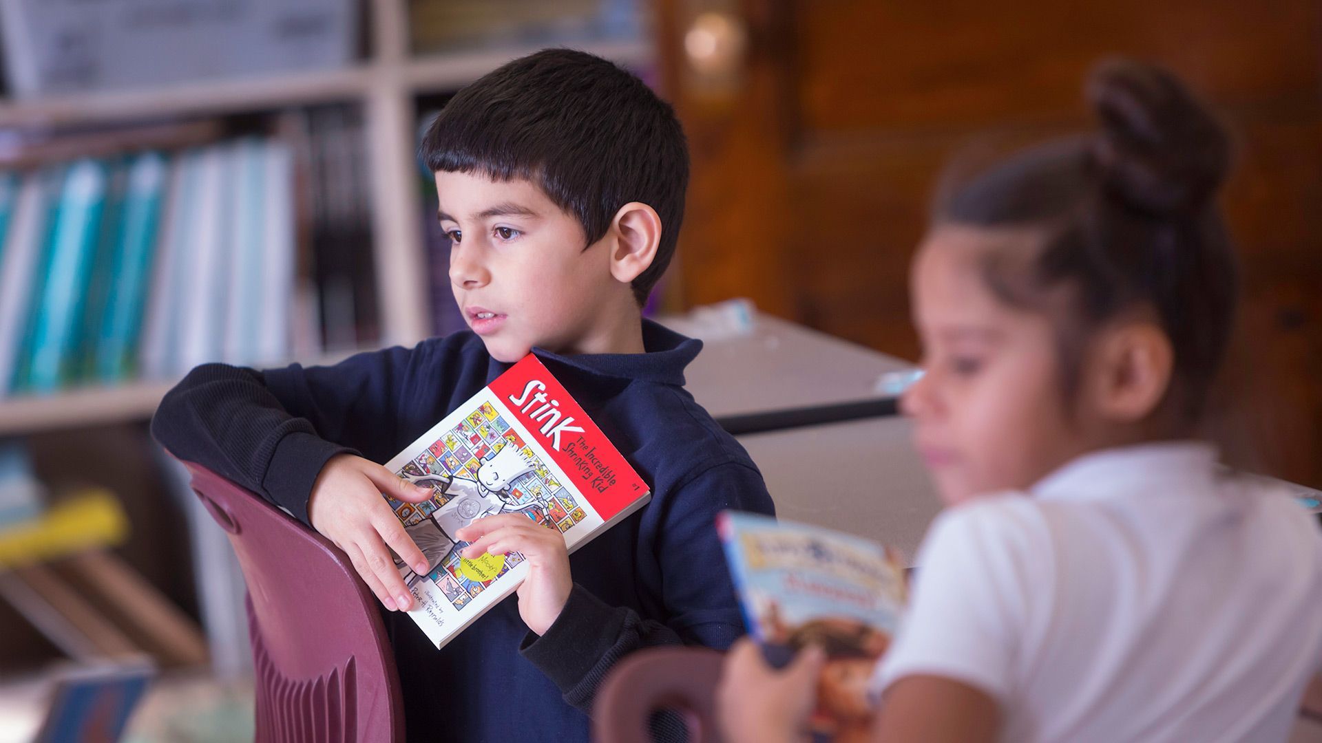 A boy holding a book that says ' snoopy ' on it