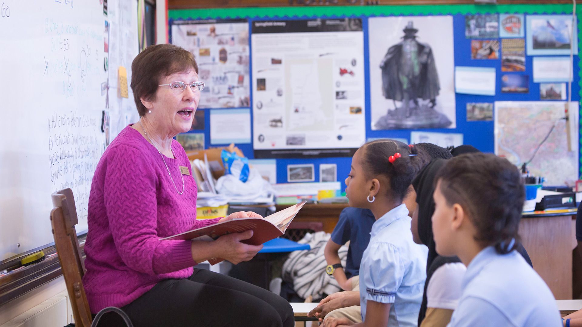A teacher is reading a book to her students in a classroom