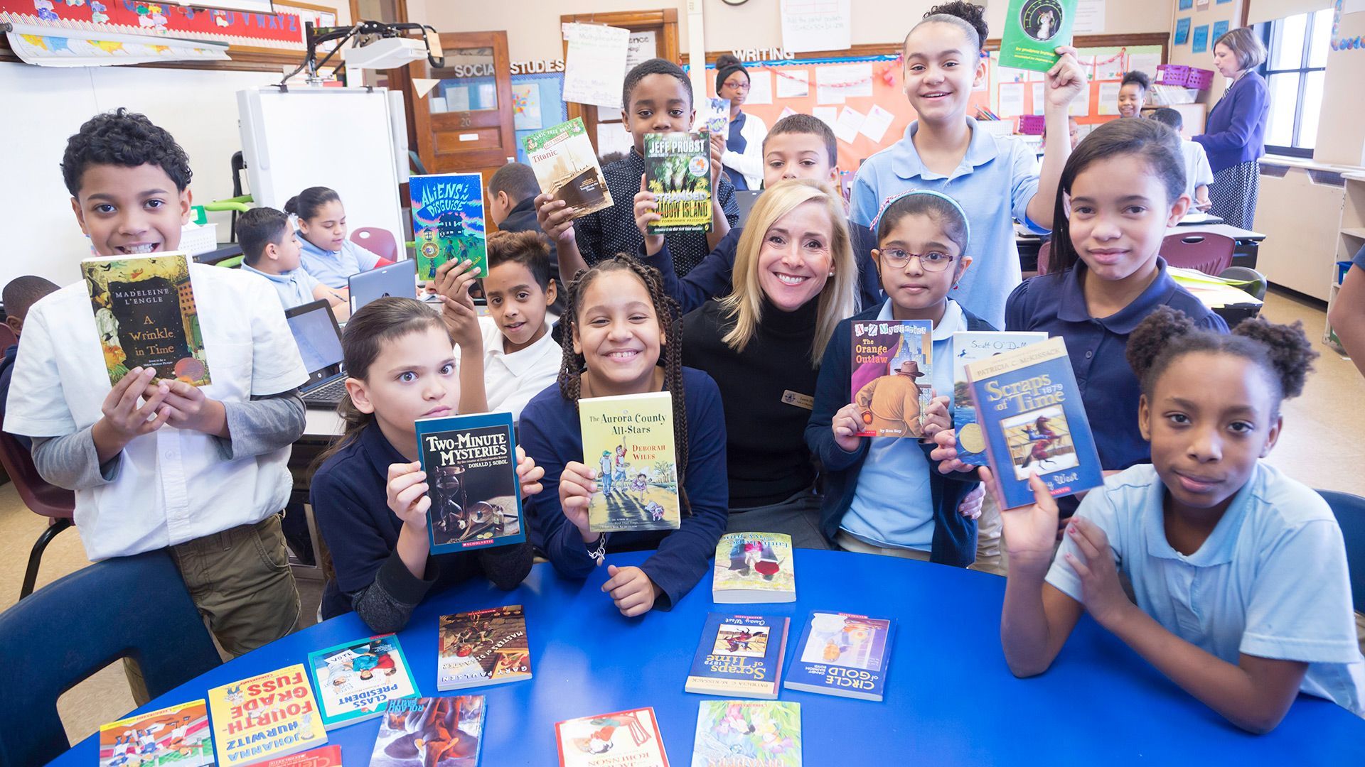 A group of children are sitting around a table holding books