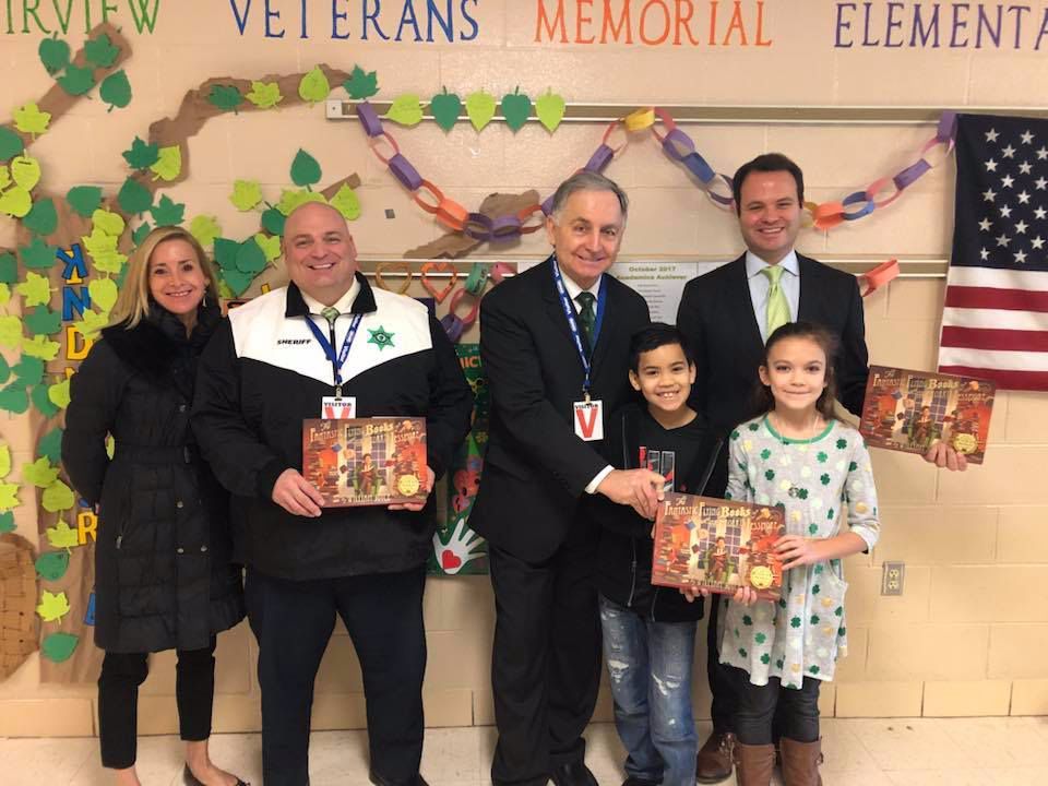 A group of people standing in front of a wall that says veterans memorial elementar