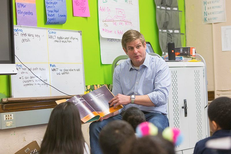 A man is reading a book to a group of children