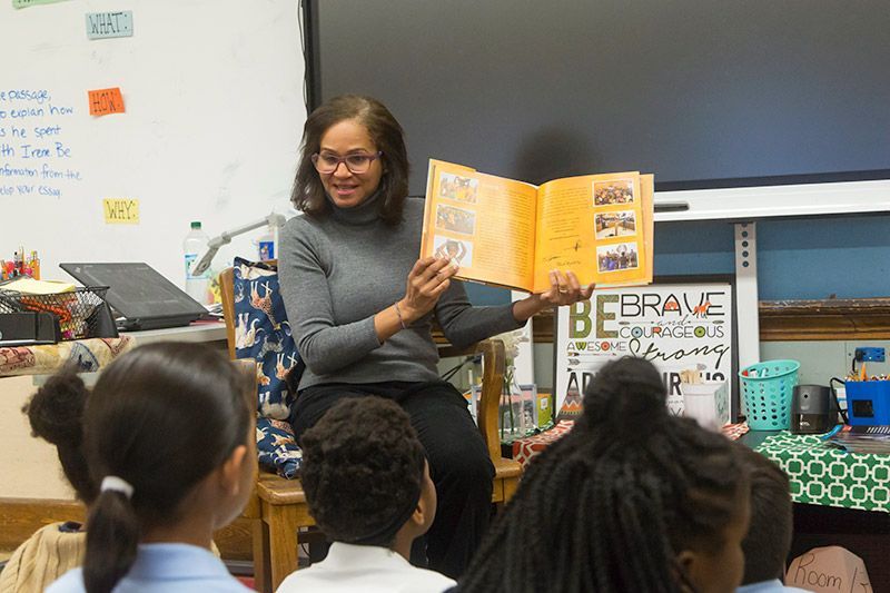 A woman is reading a book to a group of children