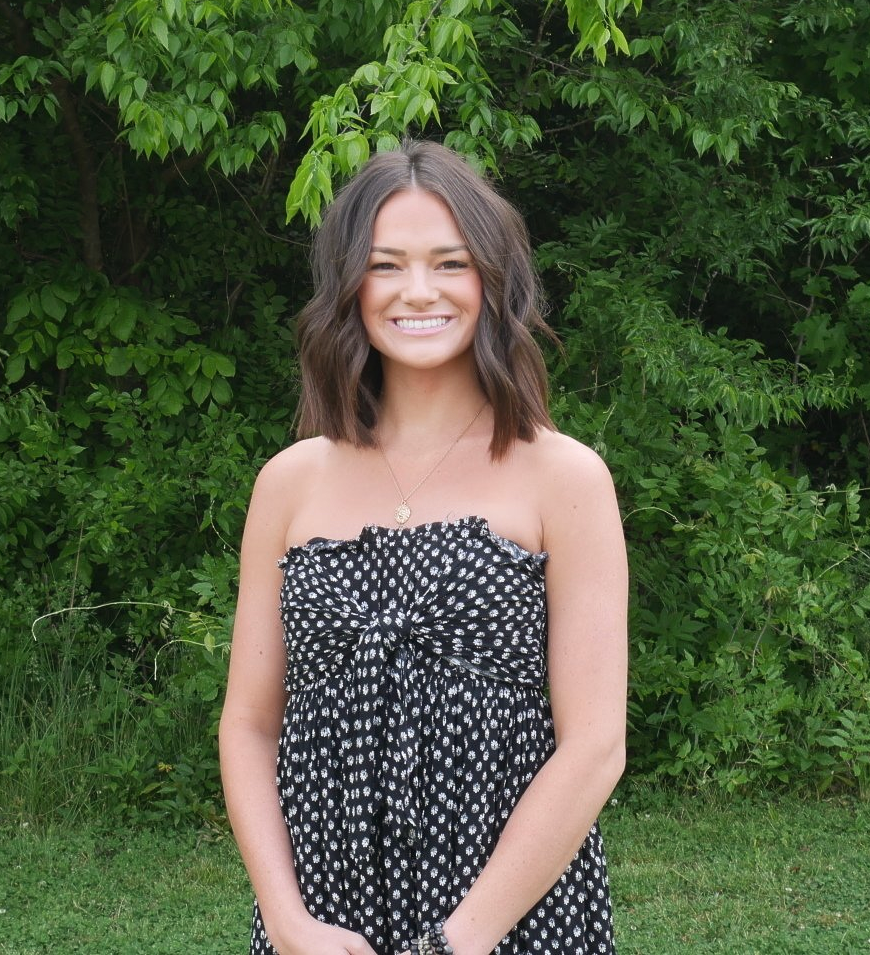 A woman in a black and white polka dot dress is smiling