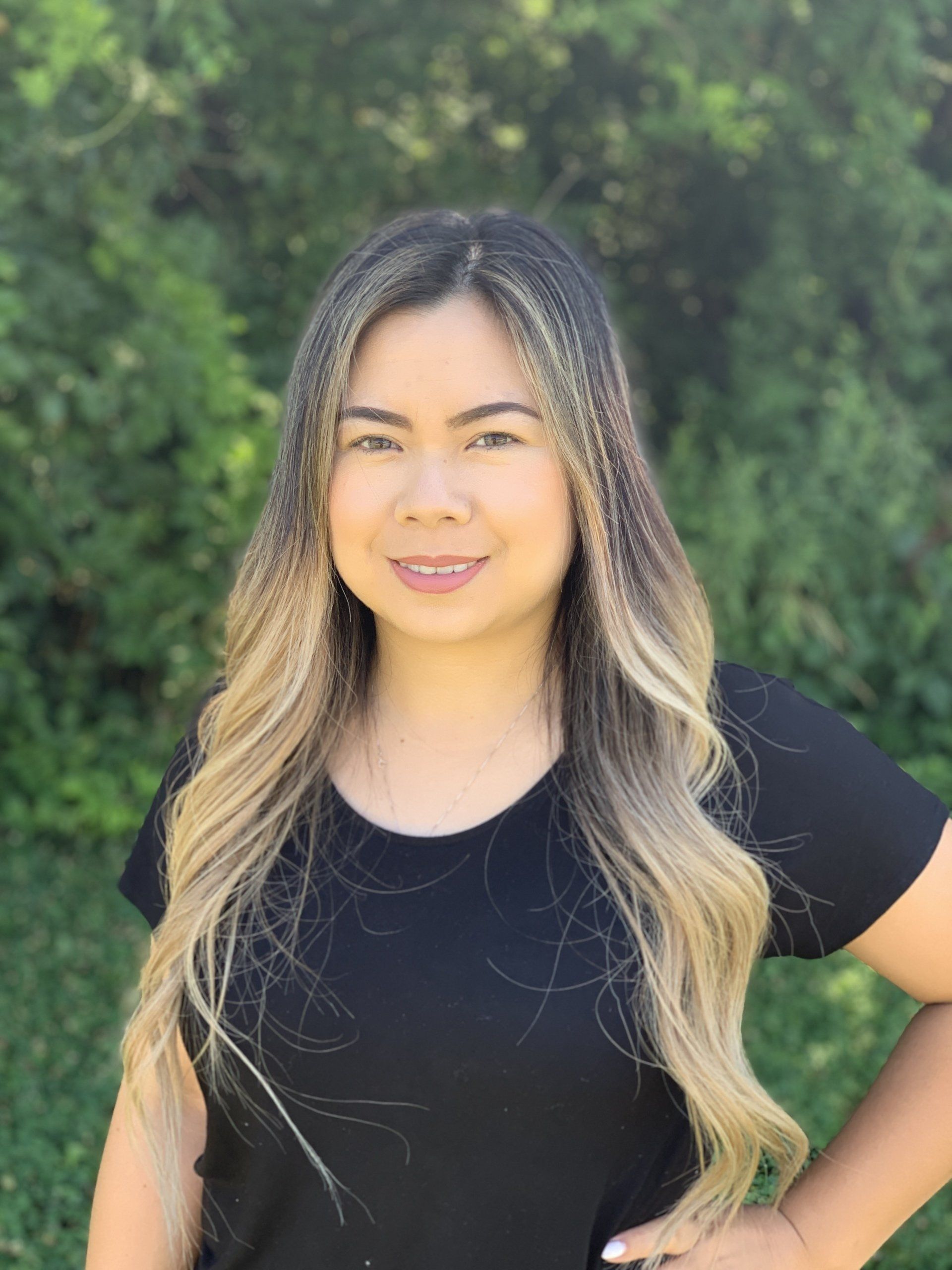 A woman in a black shirt is posing for a picture with her hands on her hips.