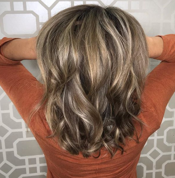 The back of a woman 's hair is shown with her hands behind her head