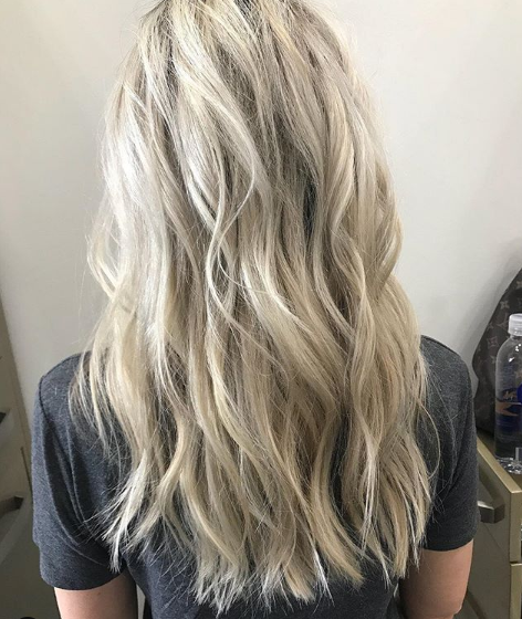 A woman with long blonde hair is wearing a gray shirt.